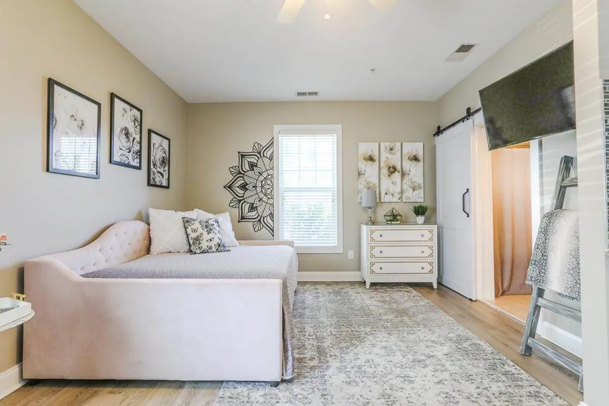A comfortable sofa bed framed by cheerful artwork and a dresser, positioned by a bright window. The space radiates a sense of calm and is perfect for relaxing or reading after a day out.