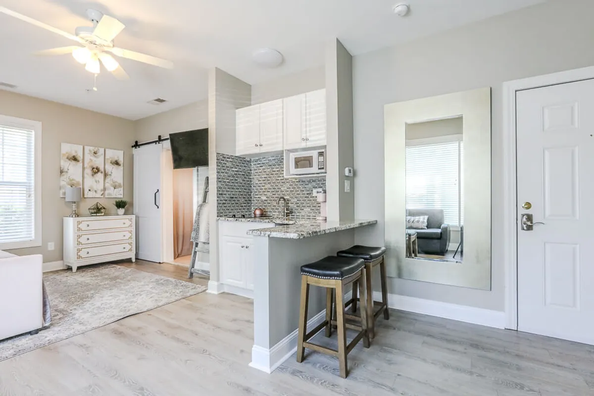 This image highlights a stylish kitchenette with a granite countertop, modern bar stools, a large mirror, and decorative wall art. The space feels comfortable and inviting, ideal for both casual family meals and relaxed gatherings after a day of exploring.